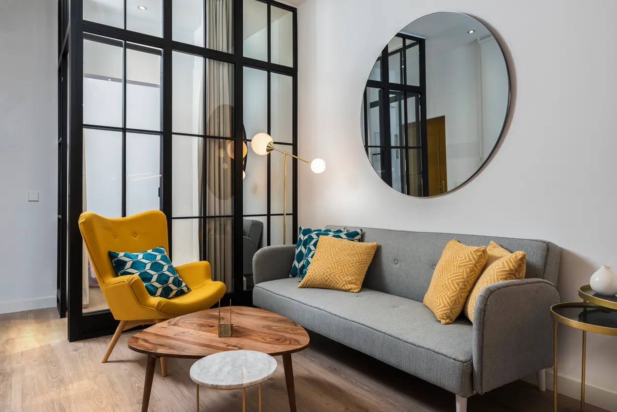 Logement étudiant moderne avec salon design, canapé gris, fauteuil jaune et table basse en bois, idéal pour une location étudiante