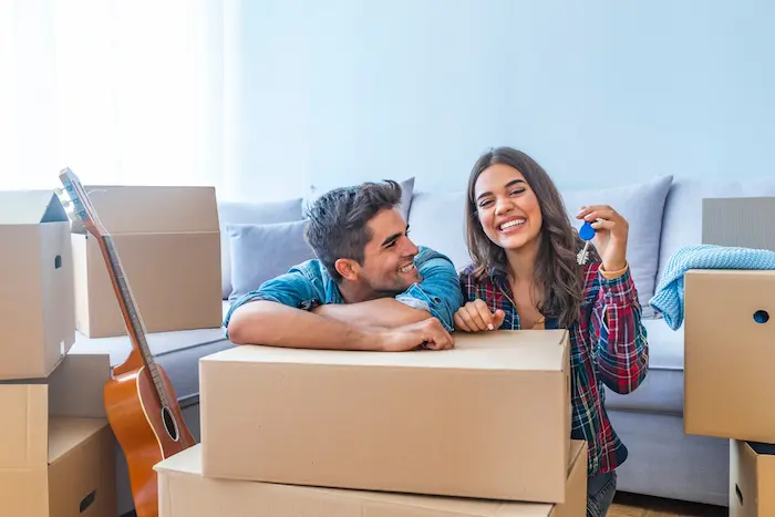 Photo d'un couple de jeunes diplômés, heureux d'emménager dans leur appartement malgré le problème de logement jeunes actifs en France