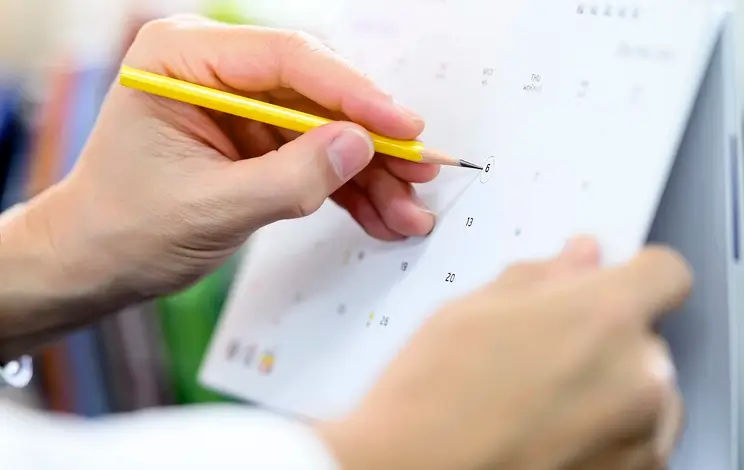 Photo d'une main qui entoure une date sur un calendrier avec un crayon, représentant le planning pour la demande logement Crous 2025/2026