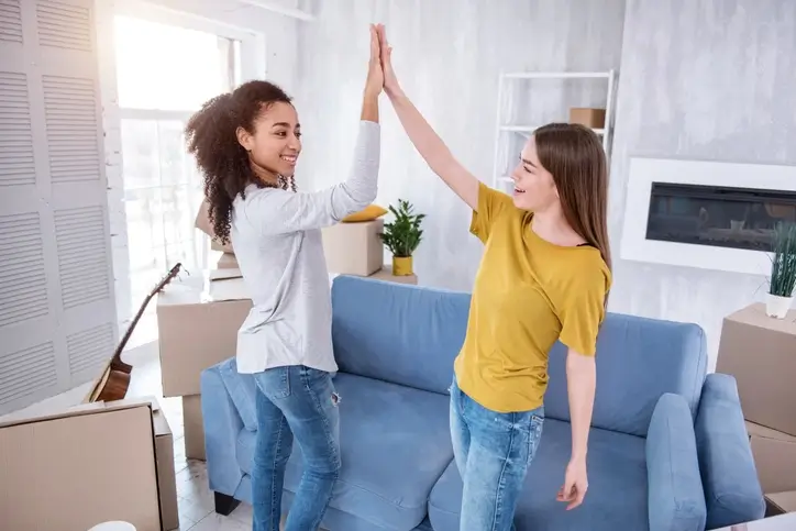 Deux étudiantes se tapent la main, contentes de s'installer dans leur nouveau logement étudiant en coliving.