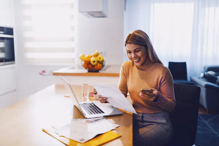 Une jeune étudiante souriante, en train de faire des simulations pour les aides au logement étudiant disponibles en 2025.