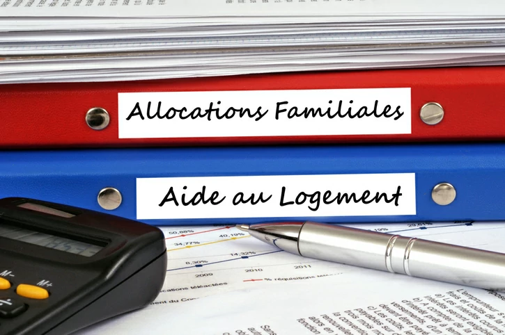 simulation aide au logement : calculer cette aide précieuse vous fera épargner un montant conséquent sur le long terme. Sur l'image, des dossiers sur les aides et une machine à calculer.
