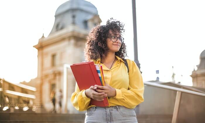 Étudiant tenant des livres à la main devant une résidence universitaire à Avignon