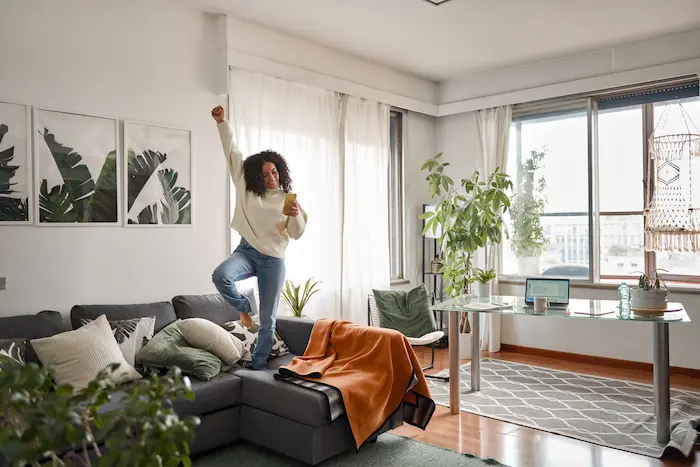Image d'une étudiante sautant sur le canapé du salon de sa résidence étudiante à Caen. Elle est contente d'avoir trouvé un logement adapté à ses attentes.