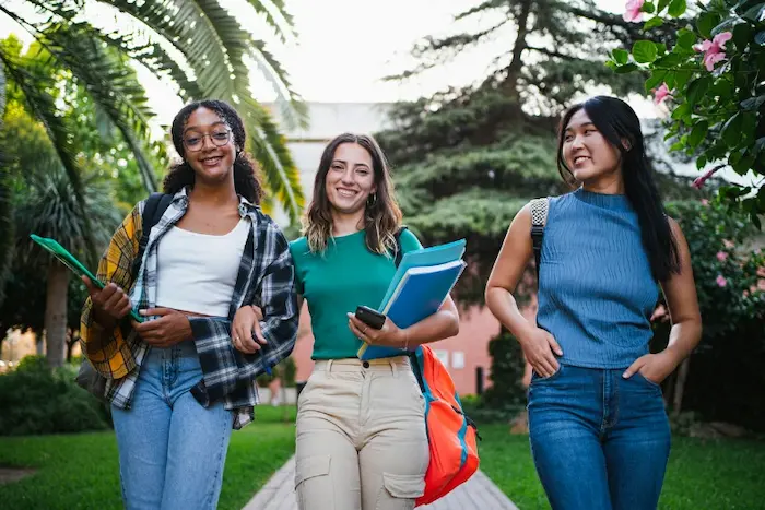 résidence étudiante à Créteil : des étudiantes reviennent d'un cours et discutent sur le chemin de la sortie dans la cours du campus. Vie d'étudiante et amitié.