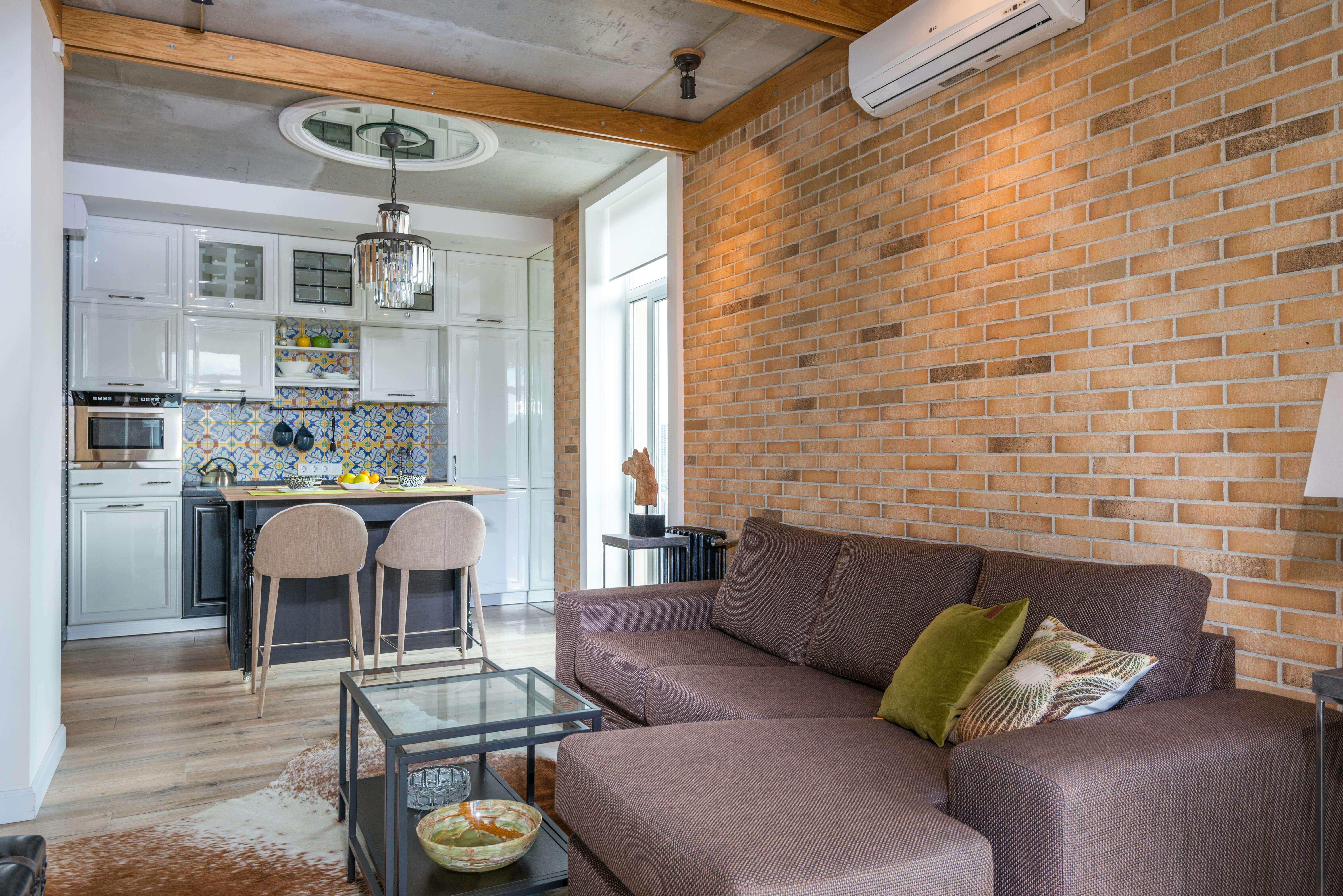 Un appartement d'une pièce avec un salon, une cuisine ouverte et une table bar haute.