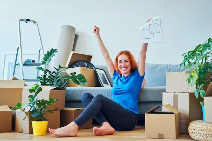 Une étudiante assise dans son salon, au milieu de ses cartons, heureuse de se retrouver dans son logement coliving à Aix-en-Provence