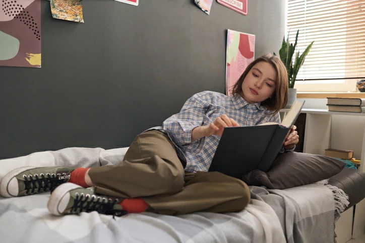 résidence étudiante à Barcelone : une étudiante est en train de lire un livre sur son lit de chambre de résidence étudiante.