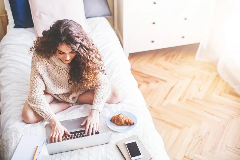 résidence étudiante à Bourg-en-Bresse : une étudiante apprend ses cours depuis son ordinateur sur son lit. Logement étudiant privée. Vie universitaire.