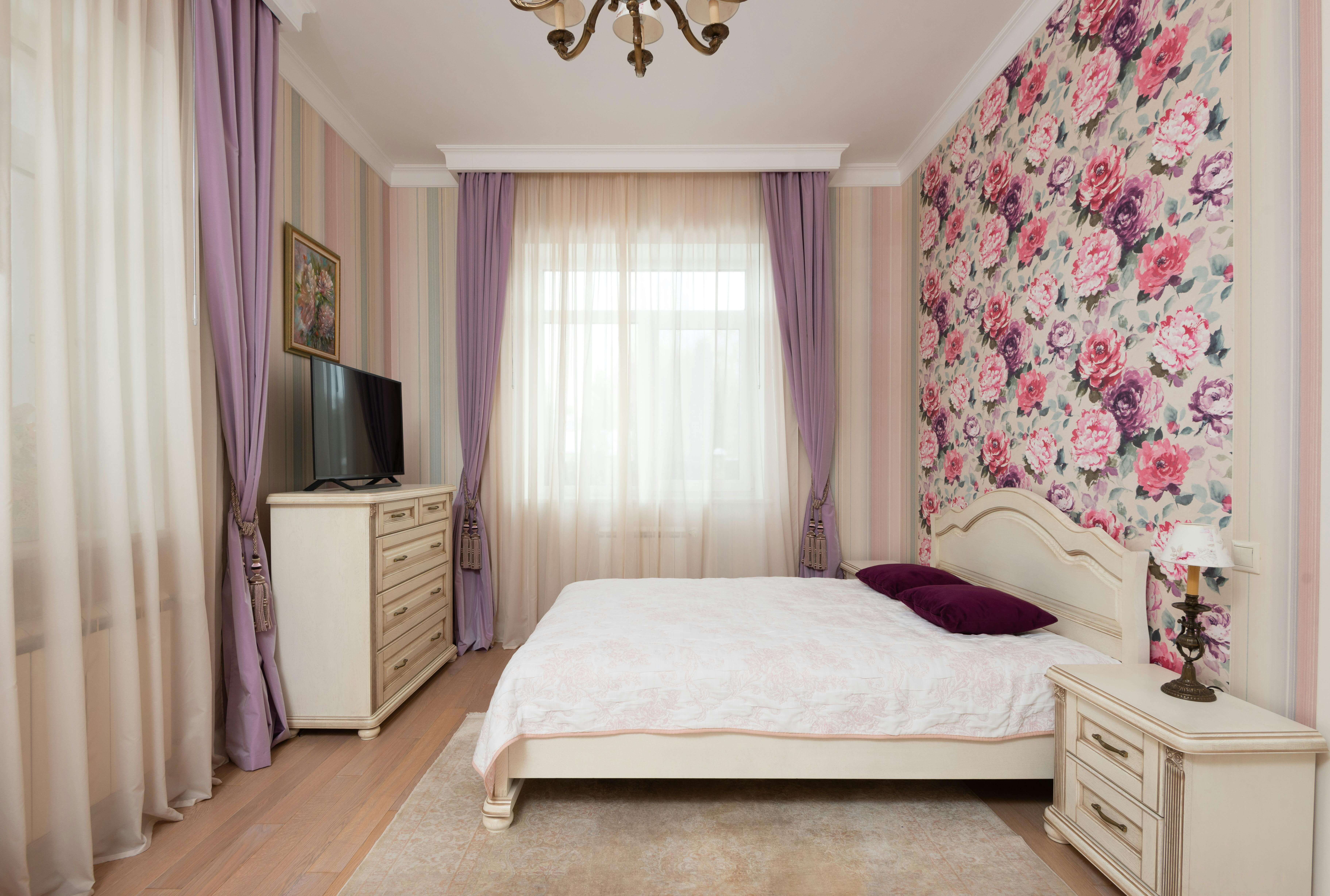 Une chambre individuelle comportant un lit, une commode, une télévision et décorée avec des couleurs vives