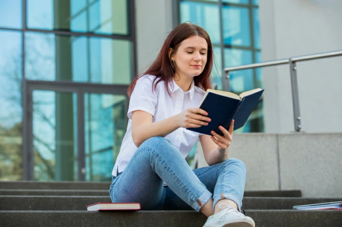 résidence universitaire à Le Havre : une étudiante lit un bouquin sur les escaliers du campus.