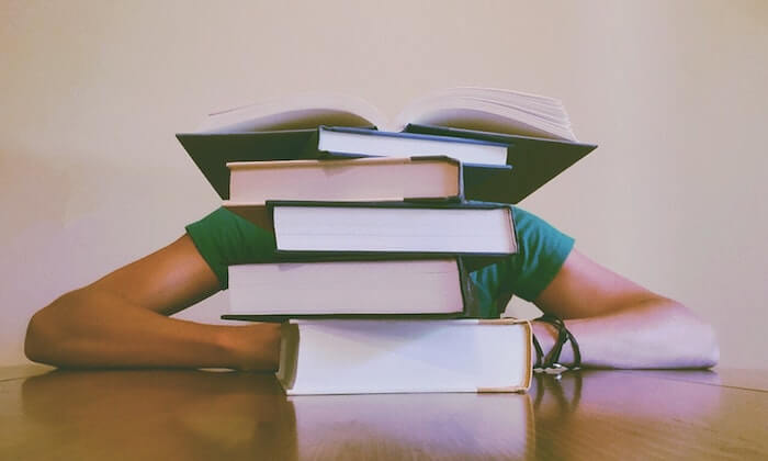 Étudiant assis caché derrière des livres