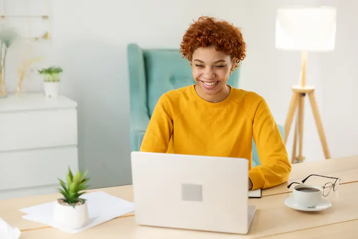 Photo d'une étudiante souriante devant son écran d'ordinateur, heureuse d'avoir trouvé un logement étudiant à Tours
