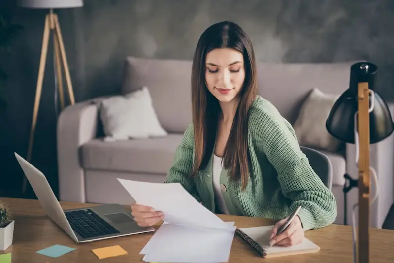 Une étudiante est assise dans son salon, en train de comparer les logements étudiants en coliving à Marseille où elle décide de finir ses études
