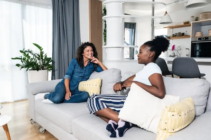 Deux étudiantes assises dans le salon de leur logement en location étudiant à Bordeaux. La photo met en valeur la convivialité entre les jeunes colocataires.