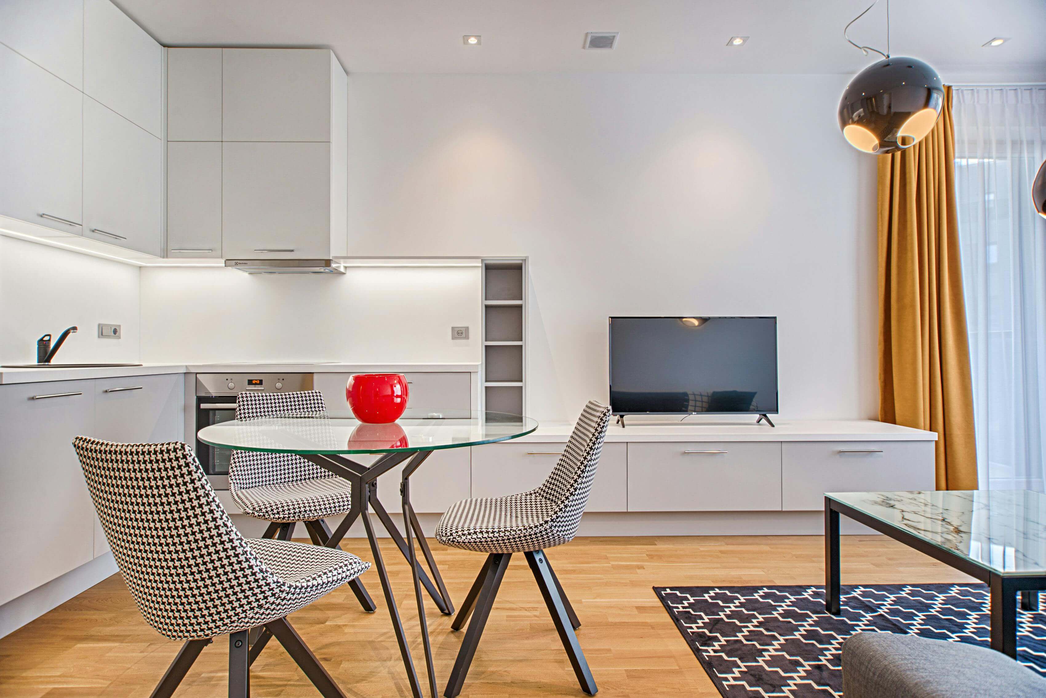 Un appartement T1 pour étudiant. Il comporte une pièce, un coin cuisine et des meubles.