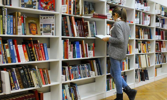 Une fille parcourt les livres dans une bibliothèque