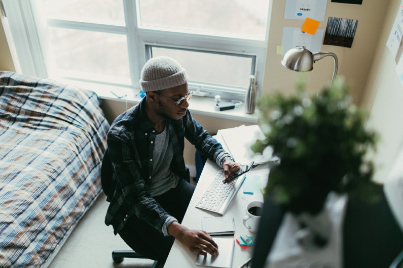 appartement étudiant à Marseille : un jeune homme habite un logement étudiant. Il est sur son bureau en train de travailler. Vie et routine d'étudiant.