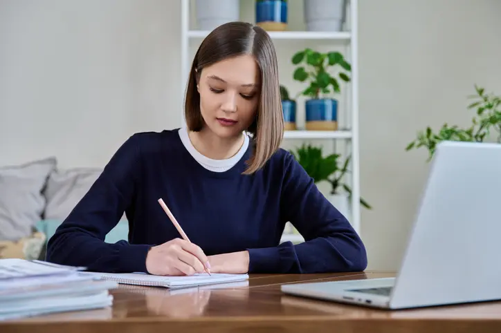 Une étudiante assise et compose un dossier en béton pour avoir un logement étudiant sans garant grâce aux conseils d'ImmoJeune