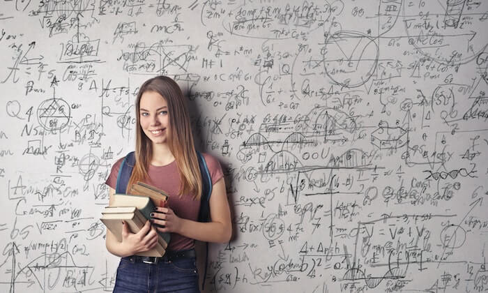 Logement étudiant Barcelone : une étudiante prend une photo devant un des tableaux du campus. Elle tient des livres et le tableau est rempli de formule mathématiques.