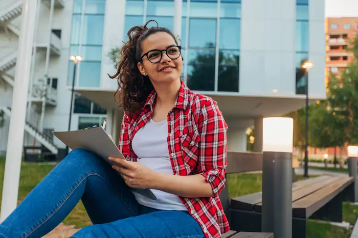 Une étudiante assise dans l'enceinte de son université. Elle vient d'Espagne et s'est informé sur la résidence étudiante étudiant étranger avant de s'installer 