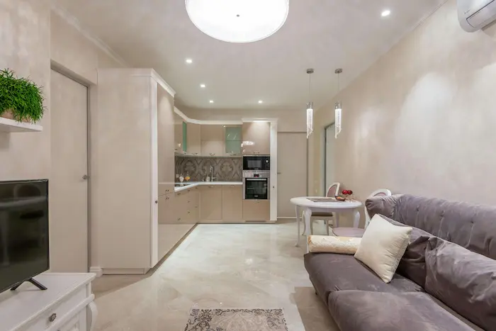 Un appartement T1 comportant un salon, une cuisine ouverte, des meubles de rangement et une télévision. Une modernité et un confort typiques à l'appartement étudiant à Grenoble 