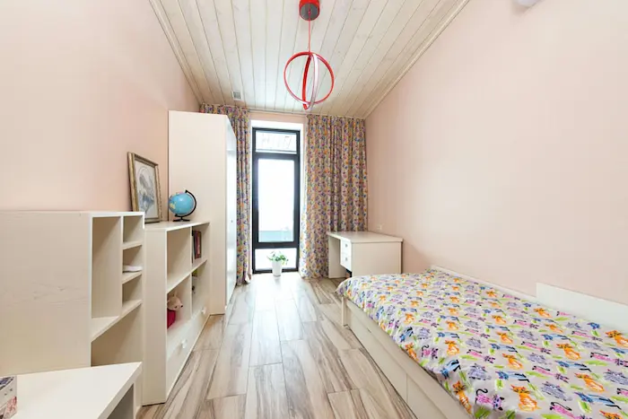 Exemple d'une chambre meublée pour étudiants. Elle comporte un lit, des étagères, un armoire et une table de bureau.