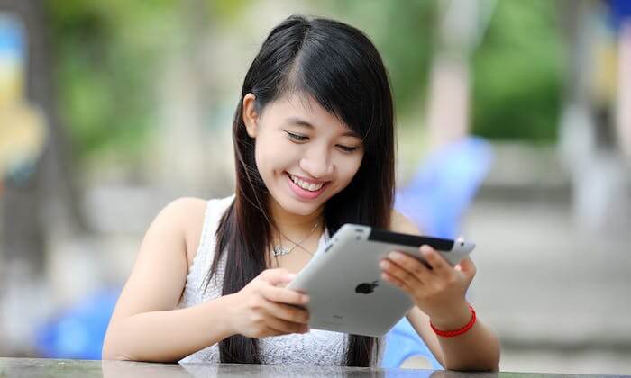Une jeune fille assise regardant sa tablette