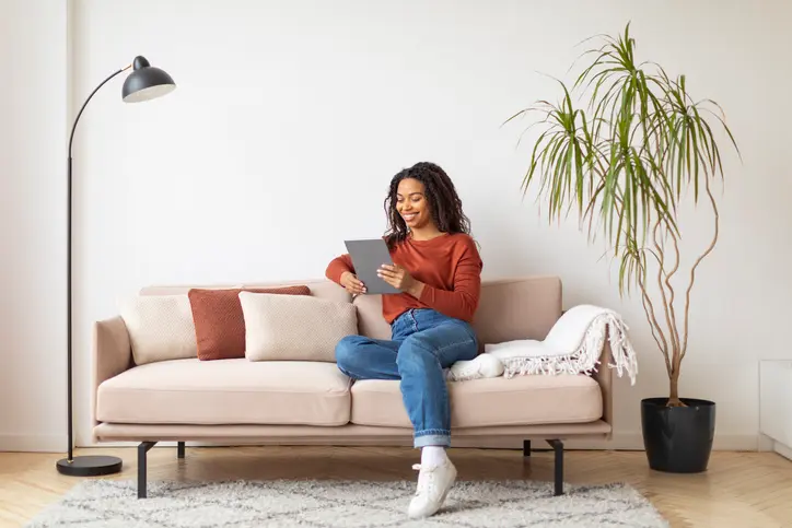 Photo d'une étudiante, assise dans le salon de son logement étudiant meublé, moderne et bien situé, qu'elle a trouvé sur ImmoJeune