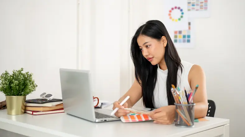 une étudiante assise à son bureau, se renseignant sur la nouvelle réforme APL
