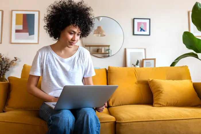 Une étudiante installée confortablement dans le salon de son studio en résidence étudiante à Tours.