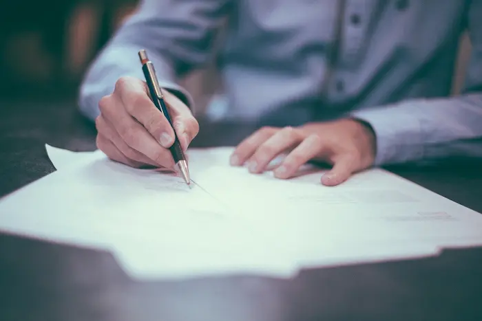 un homme en train de signer un contrat de location pour un logement étudiant en location meublée