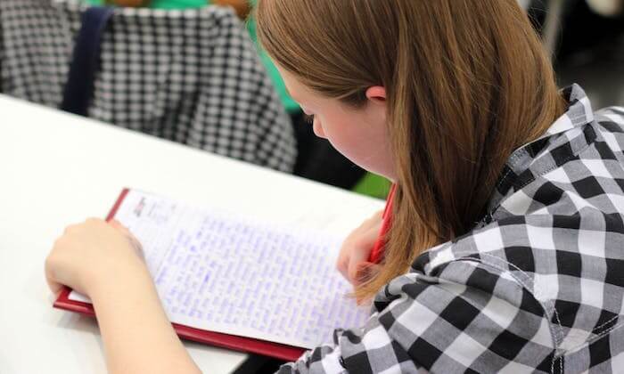 Une fille écrit un très long texte dans son cahier