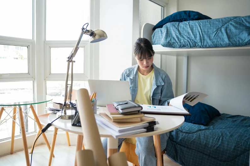 appartement étudiant à Lille : une étudiante est en train de réviser ses cours dans le dortoir d'une résidence. Logement universitaire étudiant. Etudes.